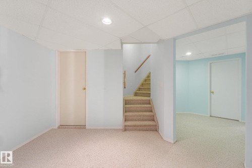 Recessed lighting, carpeted flooring, staircase with wood handrail, light blue walls - 1225 Kane Wynd Nw, Edmonton, AB - Indoor Photo Showing Other Room