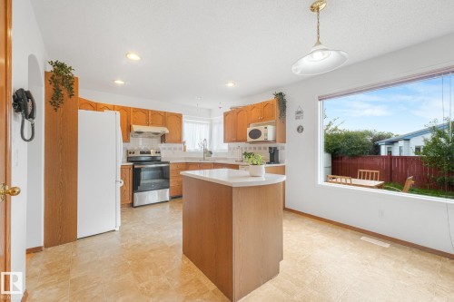 Kitchen with wood cabinetry, light countertops, and a center island with a white countertop - 1225 Kane Wynd Nw, Edmonton, AB - Indoor Photo Showing Kitchen