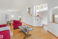 Hardwood-style flooring throughout, an arched doorway, and a multi-level staircase with wood railings - 