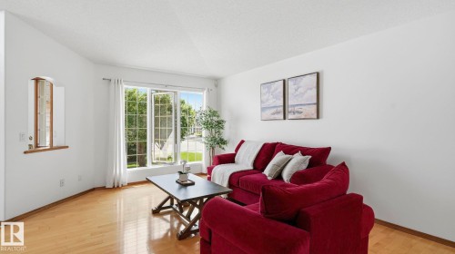 Living space featuring wood-finish flooring, white walls, and a large multi-pane window with white trim - 1225 Kane Wynd, Edmonton, AB 