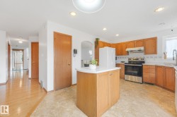 Kitchen with light wood cabinetry, a central island with countertop, and stainless steel appliances - 
