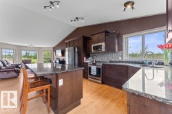 Kitchen featuring dark wood cabinetry, stainless steel appliances, and stone countertops - 