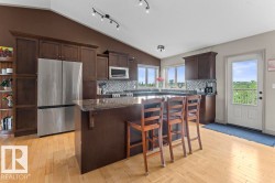 Kitchen featuring dark wood cabinetry, a central island with a granite countertop, stainless steel appliances, and light wood-finish flooring - 