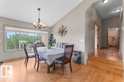 Dining area featuring light wood-finish flooring, a large picture window, vaulted ceiling, and a traditional chandelier - 