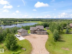 Two-story residence with a multi-car garage, separate detached two-car garage, and an additional shed, all situated on a landscaped lot with mature trees - 