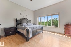 Spacious room featuring light wood-finish flooring, a vaulted ceiling, and a large multi-pane window - 