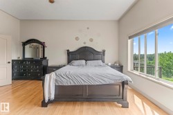 Spacious room featuring wood-finish flooring, a large window with roller shades, and light-colored walls - 