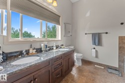 Double vanity with stone countertop and integrated sinks, under-cabinet storage, and tile flooring - 