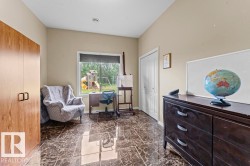 Spacious room featuring glossy marble-look floor tiles, a window with exterior views, a built-in wood-finish cabinet with modern hardware, and a white bi-fold closet door - 