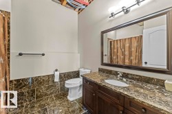 Bathroom featuring a dark wood-finish vanity with a stone-finish countertop and an undermount sink - 