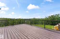 Expansive wood deck with dark finish, featuring a black metal railing and open views of surrounding greenery - 