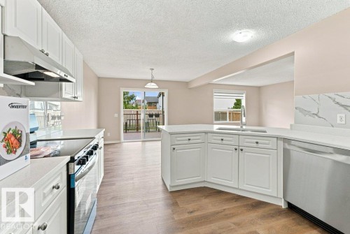 Modern kitchen featuring white cabinetry, light-toned countertops, and wood-finish flooring - 2811 33 Street, Edmonton, AB 