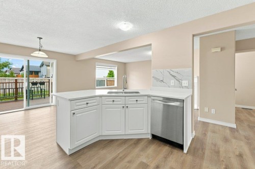 Kitchen island with white cabinetry, stainless steel dishwasher, and a white countertop - 2811 33 Street, Edmonton, AB 