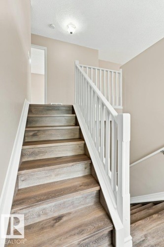 Staircase featuring wood-finish treads, white risers, and a white balustrade - 2811 33 Street, Edmonton, AB 