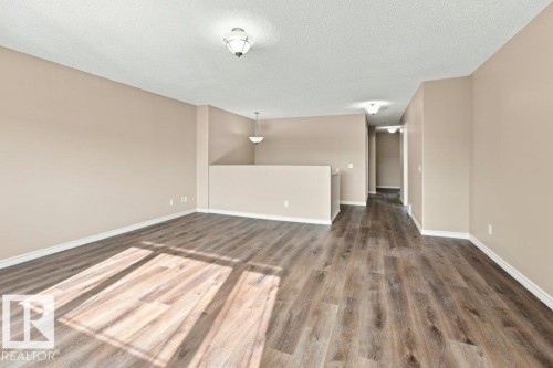 Open-concept interior featuring wood-finish flooring, neutral wall tones, and white baseboards - 2811 33 Street, Edmonton, AB 