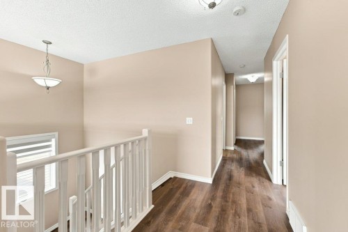 Upper level hallway featuring wood-finish flooring, light tan walls, white baseboards, and overhead lighting fixtures - 2811 33 Street, Edmonton, AB 