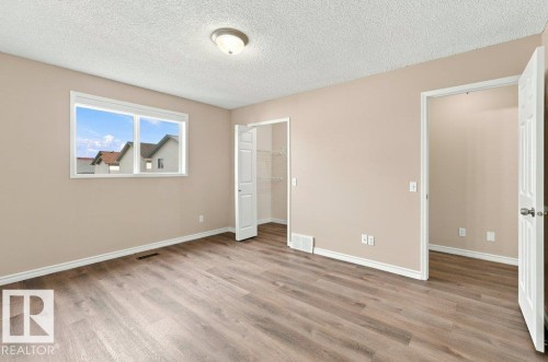 Expansive room featuring wood-finish flooring, neutral-toned walls, and white baseboards - 2811 33 Street, Edmonton, AB 