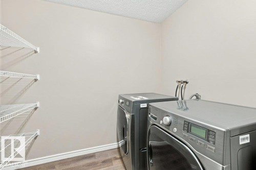 Laundry area featuring wood-finish flooring, light neutral wall paint, and white wire shelving - 2811 33 Street, Edmonton, AB 