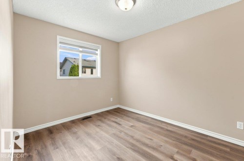 Room featuring a window with white blinds, neutral wall paint, and wood-finish flooring - 2811 33 Street, Edmonton, AB 