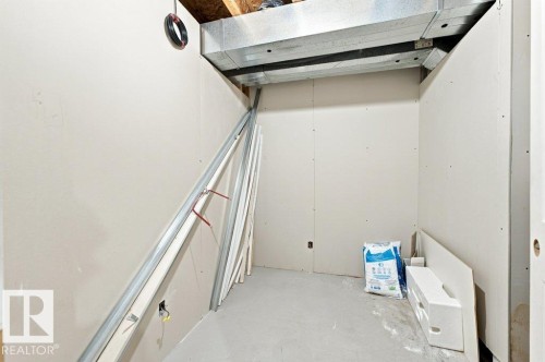 Unfinished interior space featuring drywall walls, concrete flooring, and exposed ceiling joists with visible ductwork - 2811 33 Street, Edmonton, AB 