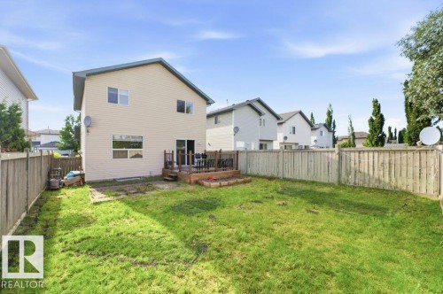 Expansive fenced backyard featuring a wood deck, wood privacy fencing, and a two-story residence with light-colored siding - 2811 33 Street, Edmonton, AB 