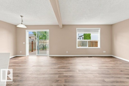 Spacious room featuring wood-finish flooring, a contemporary ceiling light fixture, and neutral wall tones - 2811 33 Street, Edmonton, AB 