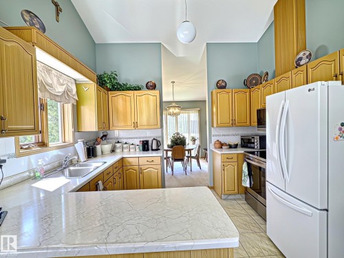 Kitchen featuring light wood cabinetry, white countertops, tile backsplash, and a double basin sink - 171 Rhatigan Road, Edmonton, AB 