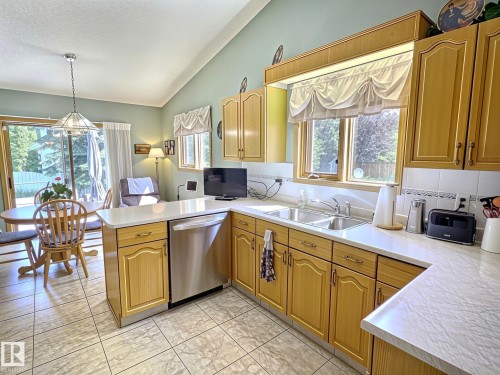 Kitchen featuring wood-finish cabinetry, light-toned countertops, and a dual basin stainless steel sink - 171 Rhatigan Road, Edmonton, AB 