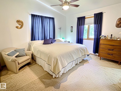 Carpeted interior with a ceiling fan featuring a light fixture, a window with wood-finish trim, and white walls - 171 Rhatigan Road, Edmonton, AB 