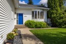 White siding exterior featuring a bright blue entry door, concrete walkway, bay window, and a green lawn - 171 Rhatigan Road, Edmonton, AB 