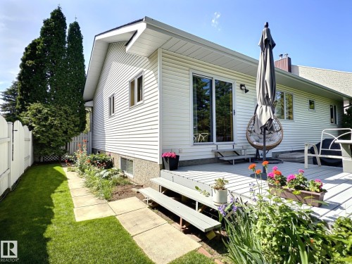 Rear exterior featuring white horizontal siding, a light-colored wooden deck, and a sliding glass door - 171 Rhatigan Road, Edmonton, AB 