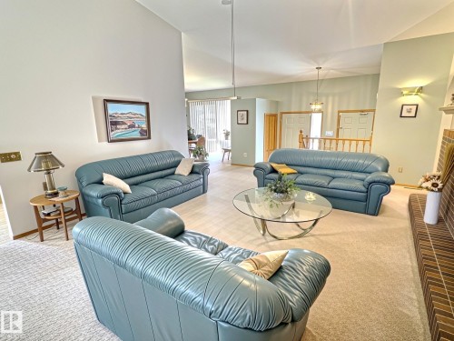 Spacious living area featuring vaulted ceilings, light neutral wall colors, and a brick fireplace - 171 Rhatigan Road, Edmonton, AB 