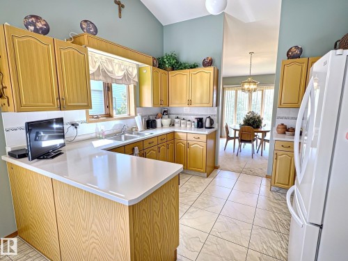 Kitchen featuring wood-finish cabinetry, light countertops, and a double basin sink - 171 Rhatigan Road, Edmonton, AB 