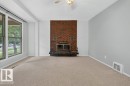 Living space featuring a prominent brick fireplace with a raised hearth - 9026 92 Street Nw, Edmonton, AB  - Indoor With Fireplace 
