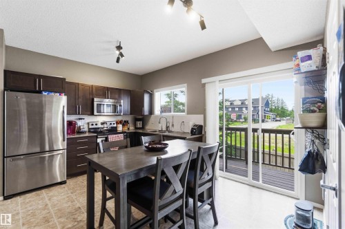 Kitchen featuring dark wood cabinetry, stainless steel appliances, and a tiled floor - 24 6520 2 Avenue, Edmonton, AB 
