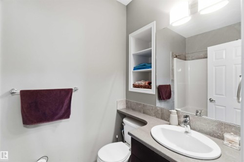 Bathroom featuring a vanity with an integrated oval sink, a large wall-mounted mirror, and overhead lighting - 24 6520 2 Avenue, Edmonton, AB 