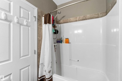 White fiberglass tub and shower combination with a curved basin and integrated shelving - 24 6520 2 Avenue, Edmonton, AB 