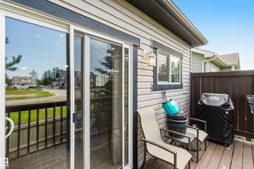 Outdoor deck featuring wood-finish flooring, a dark wood privacy screen, and light gray siding with dark trim - 24 6520 2 Avenue, Edmonton, AB 