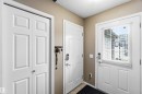 Entryway featuring a paneled door with an integrated window and blinds, light tan walls, and a textured ceiling - 24 6520 2 Avenue, Edmonton, AB 