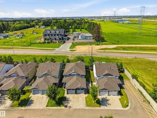 Residential streetscape featuring multiple two-story homes with attached garages, concrete driveways, and landscaped front yards - 24 6520 2 Avenue, Edmonton, AB 