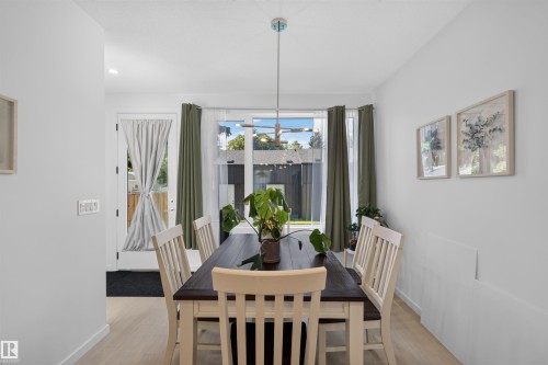 Dining area featuring light wood-finish flooring and a contemporary linear pendant light fixture - 8551 81 Avenue, Edmonton, AB 