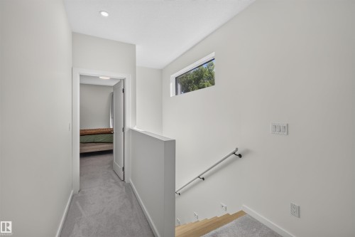 Upper-level hallway with light gray carpeting, recessed lighting, and a transom window - 8551 81 Avenue, Edmonton, AB 