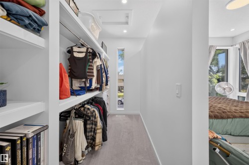 Walk-in closet featuring built-in shelving, clothing rods, recessed lighting, and a vertical window - 8551 81 Avenue, Edmonton, AB 