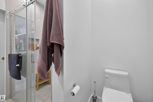 Contemporary bathroom featuring a shower enclosure with a sliding glass door and a toilet with a low-profile tank - 8551 81 Avenue, Edmonton, AB 