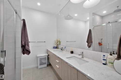 Bathroom featuring a dual vanity with light-colored wood-finish cabinetry and light-toned countertops - 8551 81 Avenue, Edmonton, AB 