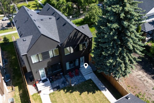 Modern exterior featuring dark vertical siding and a dark shingle roof - 8551 81 Avenue, Edmonton, AB 