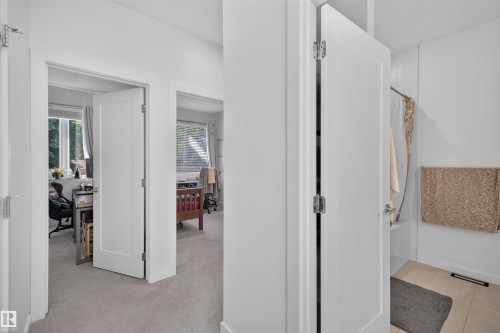 Interior hallway featuring light grey carpeting, white walls, and bright white trim - 8551 81 Avenue, Edmonton, AB 