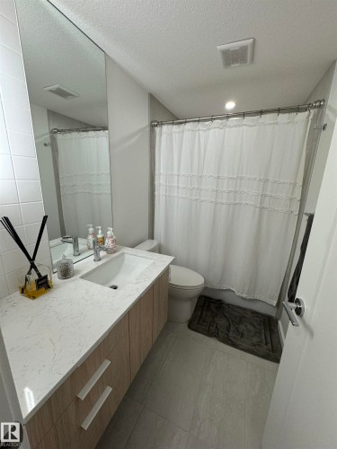 Bathroom featuring a light wood-finish vanity with a single sink and a stone-finish countertop - 8551 81 Avenue, Edmonton, AB 