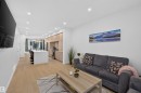Open-concept living space featuring wood-finish flooring, recessed lighting, a modern kitchen island with seating, integrated wood-finish cabinetry, and stainless steel appliances - 8551 81 Avenue, Edmonton, AB 