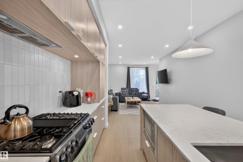 Contemporary kitchen featuring light wood-finish cabinetry, white subway tile backsplash, and light-toned countertops - 8551 81 Avenue, Edmonton, AB 